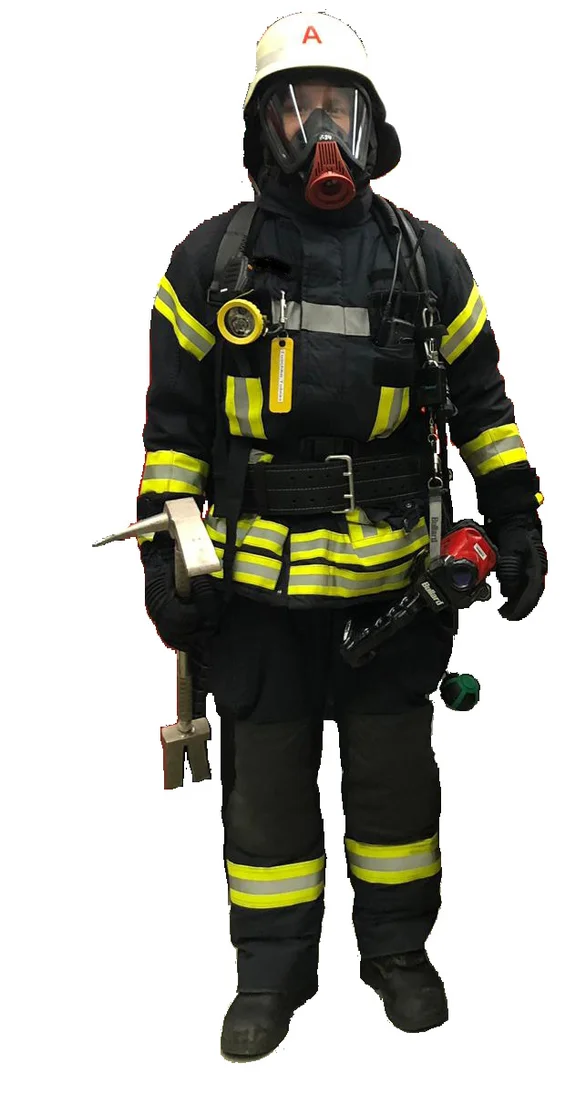 Person mit Feuerwehrhelm, Feuerwehrüberjacke, Überhose und Feuerwehrstiefeln